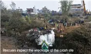  ?? Rescuers inspect the wreckage at the crash site ??