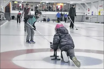  ?? SARA ERICSSON ?? Payton Roles, 7, throws the rock to her brother, Grady, 6, who gets ready to sweep it down the ice.