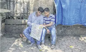  ??  ?? Two Indian men read the Assignment Abroad Times, a recruitmen­t newspaper specialisi­ng in positions in Gulf states, in Mumbai.