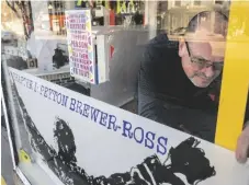  ?? JOURNAL VIA AP JOE PHELAN/THE KENNEBEC ?? Peter Precourt levels a sign in the front window for the “There Goes My Hero: Chapter 1 Peyton Brewer-Ross” show on Thursday at Art:Works on Main gallery in Winthrop, Maine.