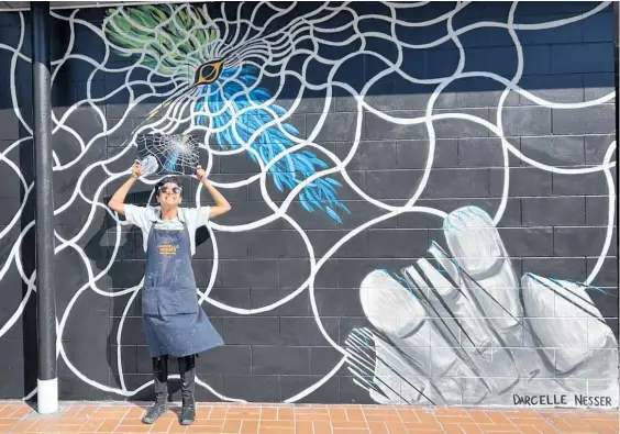  ?? ?? Palmerston North artist Darcelle Nesser with her latest mural, I Accidental­ly Dropped My Hands in Some Gravitatio­nal Waves. She wants the mural to spark awe at the universe and all that lies beyond.