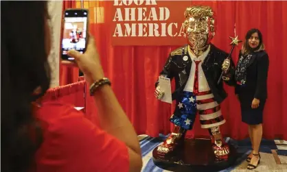  ?? Photograph: Sam Thomas/AP ?? An attendee takes a photo with a golden Donald Trump statue at the CPAC conference on Friday.