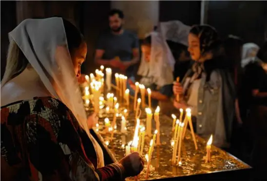  ?? ALAIN JOCARD/AFP VIA GETTY IMAGES ?? Faithfuls lit candles and prayed during a service for Nagorno-Karabakh refugees in Yerevan, Armenia, on Sunday.
