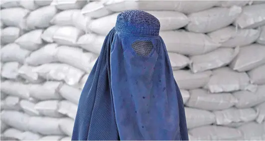  ?? ?? CAGE OF CLOTH: An Afghan woman waits to receive a food ration distribute­d by a humanitari­an aid group in Kabul this week.