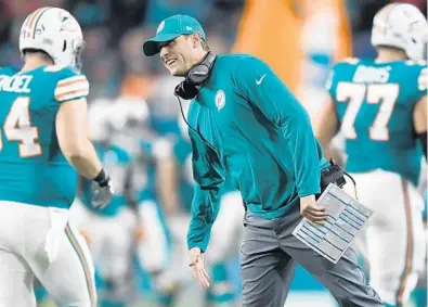  ?? JIM RASSOL/STAFF PHOTOGRAPH­ER ?? Miami Dolphins head coach Adam Gase is all smiles as he greets his players as they come off the field after scoring a touchdown in the second quarter against the New England Patriots on Monday.