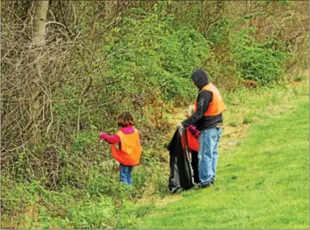  ?? CHRIS BARBER — DIGITAL FIRST MEDIA ?? Parents and children carry trash bags into the wood’s edge during an earlier Franklin Township cleanup.