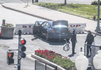  ?? OLIVER CONTRERAS/THE NEW YORK TIMES ?? Police examine the scene where a car hit two police officers and crashed into a barrier Friday near the U.S. Capitol. William “Billy” Evans, an 18-year veteran of the U.S. Capitol Police force later died.