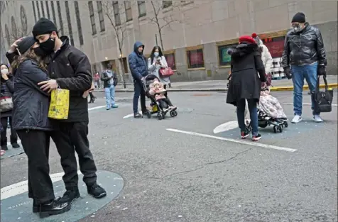  ?? Seth Wenig/Associated Press ?? People wait in socially distanced circles for the chance to get a glimpse of the Rockefelle­r Center Christmas tree Friday in New York. The pandemic upended Christmas traditions, but determinat­ion and imaginatio­n kept the day special for many.