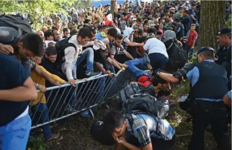  ?? JEFF J .MITCHELL/GETTY IMAGES ?? Migrants seeking to board a train force their way through police lines in Tovarnik, Croatia, after waiting hours in the hot sun.