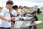  ?? MAYA WASHBURN/ALM BEACH POST ?? Jupiter High School marching band members Connor Murphy, left, Camille Lyn and Kat Jones play their xylophones during practice on Monday, the day the band received a $15,000 grant from the nonprofit Save Our Musicians.