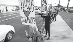  ??  ?? Jeanne Carney waves at cars on Saturday during a protest against Dolphinari­s at Via de Ventura and Pima Road in Scottsdale.
