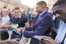  ?? LUDOVIC MARIN/POOL PHOTO VIA AP ?? France’s Kylian Mbappe, center, signs autographs during a reception at the Elysee Presidenti­al Palace in Paris Monday.