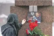  ?? DMITRI LOVETSKY/ASSOCIATED PRESS ?? A woman touches a photo of Alexei Navalny after laying flowers paying the last respect to him at the Memorial to Victims of Political Repression in St. Petersburg, Russia, on Saturday.