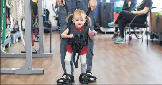  ?? CP PHOTO ?? Evelyn Moore is hooked up to her dad Brad Moore as they take part in a walking exercise at the Reyu Paralysis Recovery Centre in Edmonton Alta., April 4. Evelyn was permanentl­y paralyzed below her arms after a bout with cancer.