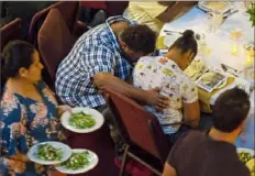  ??  ?? Marcus Young, center, bows his head with his wife, Theresa Young, as they pray Tuesday before a weekly dinner for the homeless hosted by First Presbyteri­an Church.