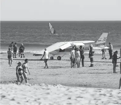  ?? ARMANDO FRANCA / THE ASSOCIATED PRESS ?? People walk past a plane parked by the sea after an emergency landing at Sao Joao beach in Costa da Caparica, Portugal, on Wednesday. The landing on the packed beach killed a man and a child who were sunbathing.