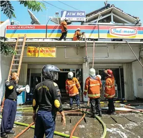  ?? HANUNG HAMBARA/JAWA POS AKHMAD RIZAL/JAWA POS ?? GERAK CEPAT: Petugas damkar melakukan pembasahan di minimarket di Dukuh Kupang kemarin.