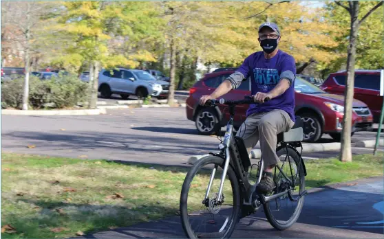  ?? MICHILEA PATTERSON – FOR MEDIANEWS GROUP ?? John Wolfe rides a bike along the Schuylkill River Trail at Pottstown Riverfront Park while wearing a mask.