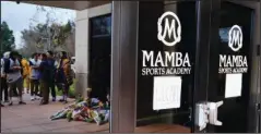  ?? The Associated Press ?? NO MORE MAMBA: Los Angeles Lakers fans and a memorial are reflected in the window of the Mamba Sports Academy in Thousand Oaks, Calif., following reports of NBA star Kobe Bryant’s death in a Jan. 26 helicopter crash in southern California. The Southern California sports academy previously co-owned by the late Bryant has retired his “Mamba” nickname and rebranded itself nearly four months after the basketball icon’s death in a helicopter crash. The Thousand Oaks-based facility announced Tuesday it would return to its original name of Sports Academy and retire the “Mamba” name to the rafters.