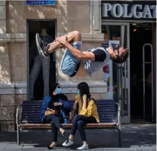  ?? (Yonatan Sindel/Flash90) ?? A MASKED man does a flip yesterday while practicing freerunnin­g on Jaffa Street in downtown Jerusalem. More than 8,500 people have been diagnosed with coronaviru­s thus far in July, while 8,395 received a positive diagnosis in all of June.