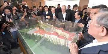  ??  ?? Najib takes a closer look at a model of the new Sekolah Menengah (SM) Kuen Cheng building after launching the school redevelopm­ent project.— Bernama photo