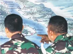  ??  ?? Members of the Indonesian rescue team look at a map as they prepare to deploy sonar equipment (not pictured) to help search for missing passengers at the Lake Toba ferry port in the province of North Sumatra. — AFP photo
