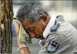  ?? AP 2023 ?? CHINA: A security guard suffering from the heat wears an electric fan on his neck as he wipes away his sweat on a hot July day in Beijing.