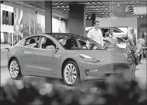  ?? AP ?? A customer talks with a sales associate last summer beside a Tesla Model 3 in a showroom in Denver.