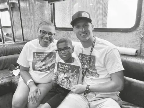  ?? STEVE MEGARGEE/ AP ?? SHELETTA BRUNDIDG, HER SON BRANDON,AND NASCAR DRIVER BRANDON BROWN gather Saturday at Road America in Elkhart Lake, Wis. Sheletta Brundidge wrote a children’s book in her son’s honor after Brandon Brundidge saw “Let’s go, Brandon” signs and assumed they were cheering him on. The cover of Brundidge’s book decorated the hood of Brandon Brown’s car (photo below) for his Xfinity Series race Saturday at Road America.