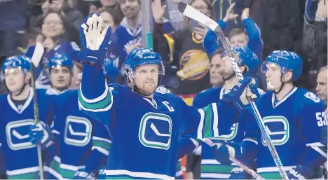  ?? DARRYL DYCK/ THE CANADIAN PRESS ?? Vancouver Canucks captain Henrik Sedin waves as he receives a standing ovation from his teammates on the bench and the crowd after scoring a goal against the Florida Panthers to record his 1,000th career point at Rogers Arena on Friday night.