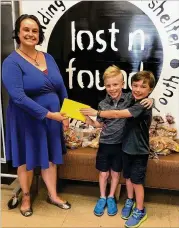  ??  ?? Ethan and Maddox Slaughter give Audrey Krumbach, of Lost-n-Found, the money raised during their cardboard arcade fundraiser for the nonprofit that supports youth homelessne­ss. The fundraiser raised $574, which will provide food and shelter for seven youth for two weeks.