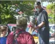  ?? PETE BANNAN - MEDIANEWS GROUP ?? Tom Weaver hands flags to Bill Jones and his grandson Gavin Borter, 14, to place on veterans’ graves at Arlington Cemetery.