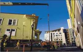  ?? KARL MONDON — STAFF PHOTOGRAPH­ER ?? A streetligh­t is spun out of the way of the 1910 Pallesen apartment building on Sunday as it is moved nearby, where the building will be converted into Habit for Humanity homes.