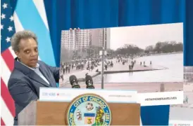  ?? TYLER LARIVIERE/SUN-TIMES ?? Mayor Lori Lightfoot displays a photo of crowds along Lake Michigan at a news conference Thursday at which she explained her order to close the lakefront.