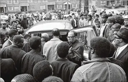  ?? ASSOCIATED PRESS ?? People gather around a hearse after a short memorial service for King in Memphis on April 5, 1968. While Memphis was preparing King’s body, Atlanta was preparing for his funeral, which was held on April 9.