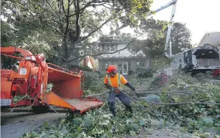  ??  ?? Christian’s Tree Service cleans up a tree that fell on a house Wednesday in Ottawa. The storm created a downdraft of wind that descended sideways from the upper atmosphere, says Environmen­t Canada’s Peter Kimbell.