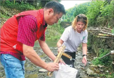  ?? HE ZHUTAO / FOR CHINA DAILY ?? Tori Widdowson, a civil river chief of Houwu village in Heqing county of Zhejiang province, works together with a local volunteer to clean garbage in a river.