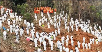  ?? HUANG XIAOBANG / XINHUA ?? Search and rescue team members pause to mourn for plane crash victims by observing three minutes of silence, on March 27, in Tengxian county, Guangxi Zhuang autonomous region.