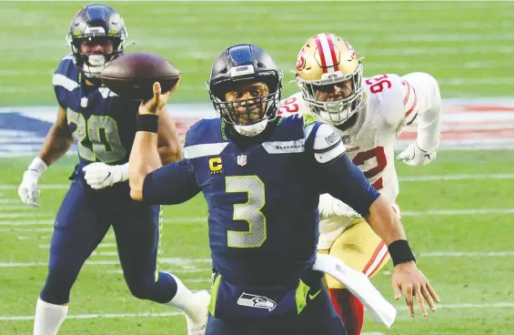  ?? JOE CAMPOREALE/ USA TODAY SPORTS ?? Russell Wilson tosses a TD pass in Sunday's 26-23 win over the 49ers. The Seahawks QB was hot to start the season, but cooled off in the second half.