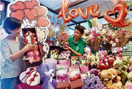  ??  ?? Blooms of love: Lau (left) and Seah arranging their boxed flower bouquets for Valentine’s Day at their shop in Burmah Road, Penang.