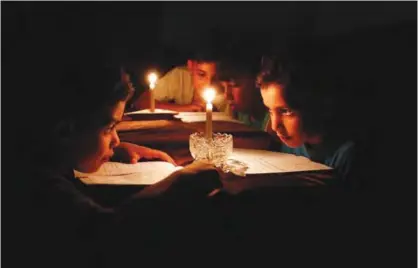  ??  ?? GAZA: This photo taken on June 13, 2017 shows Palestinia­n children at home reading books by candleligh­t due to electricit­y shortages in Gaza City. —AFP