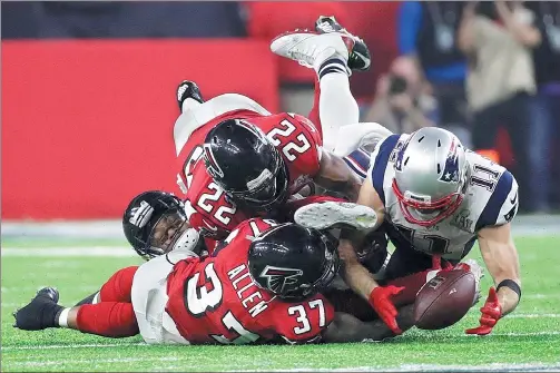  ?? PATRICK SEMANSKY / AP ?? New England Patriots wide receiver Julian Edelman is gang tackled by a trio of Atlanta Falcons as he hauls in the ball just before it hits the turf late in the fourth quarter of the Patriots’ 34-28 overtime victory in Super Bowl LI in Houston on Sunday.