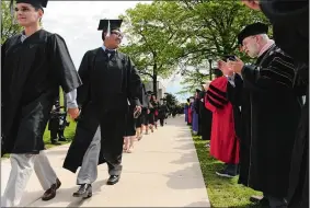  ?? DANA JENSEN/THE DAY ?? During the procession­al a graduate and a faculty member greet each other as the graduates pass the faculty lined up on both sides of the walkway during the Connecticu­t College graduation ceremony on Tempel Green.