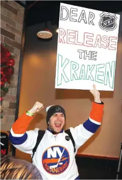  ?? AP PHOTO/ELAINE THOMPSON ?? Max Rubin cheers, holding a sign in favor of the proposed team name “Kraken” Tuesday after the announceme­nt of a new NHL team in Seattle.