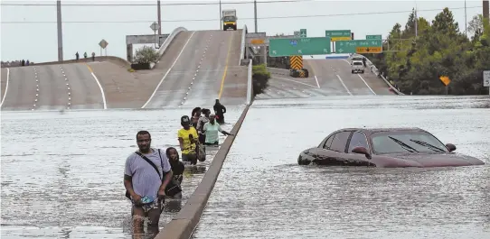  ?? AP PHOTO ?? TRYING TO ESCAPE: Evacuees wade through a flooded section of Interstate 610 in Houston yesterday. Remnants of Tropical Storm Harvey poured devastatin­g rain into the city as thousands of people fled to rooftops or higher ground to be rescued.