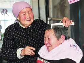  ?? XIAO YONGJIE / FOR CHINA DAILY ?? Sun Yincong combs the hair of her daughter-in-law Ren Caimei at their home in Yuncheng, Shanxi province.