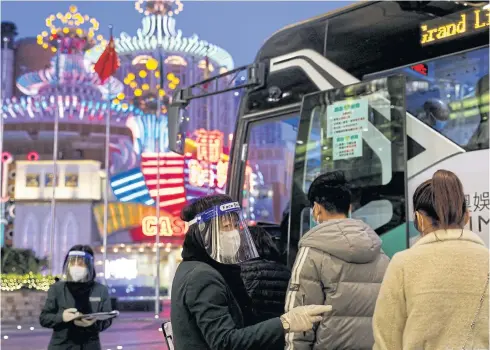  ?? REUTERS ?? A staff member wearing a protective mask and a face shield guides people on to a shuttle bus at Grand Lisboa Casino, which is operated by SJM Holdings in Macau on Dec 29.