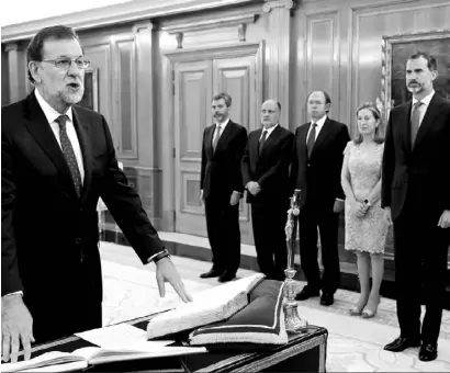  ?? Photo DPA ?? Sr Rajoy, with one hand on the Spanish Constituti­on and the other on the Bible open in the Book of Numbers, swears loyalty as PM before King Felipe