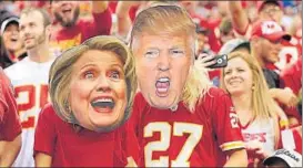  ??  ?? Sports fans wear Hillary Clinton and Donald Trump masks at a game in Missouri on Sunday.