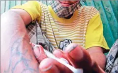  ?? HENG CHIVOAN ?? An addict uses a needle to inject drugs on a side street of Phnom Penh in 2009.